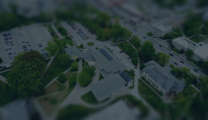 Aerial view of a suburban neighborhood with houses, trees, streets, and a parking lot.
