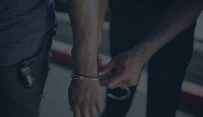Two people handcuffed together, one holding a black handgun in a dark scene