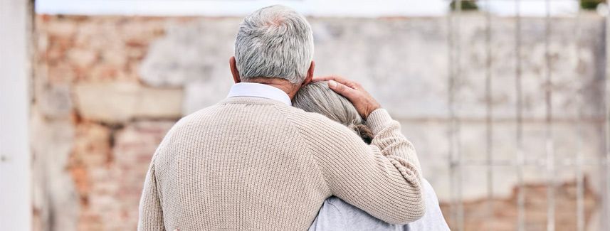 Two people embracing outdoors in front of a stone wall