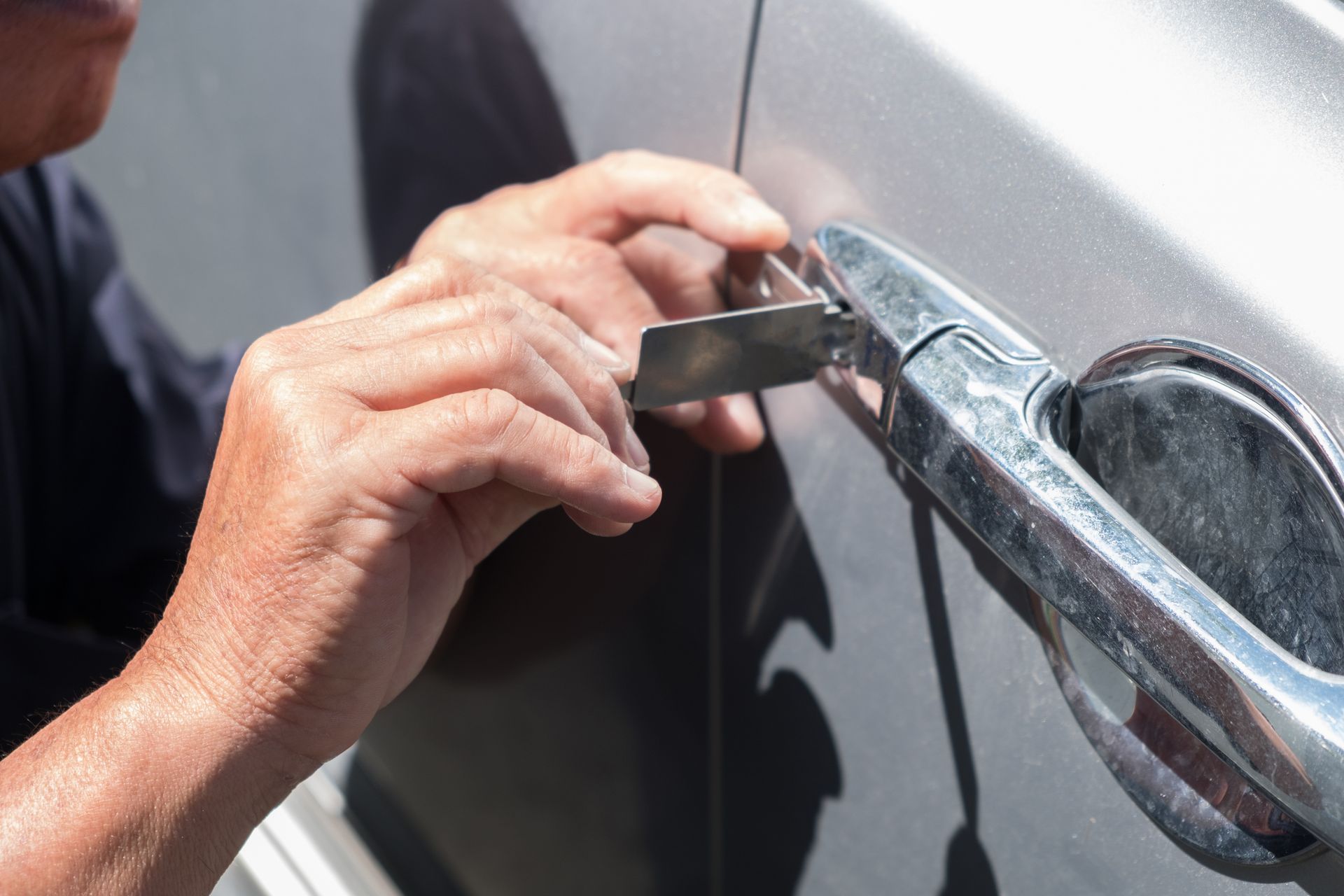 Hands using a key to unlock a silver car door handle Hands using a key to unlock a silver car door handle