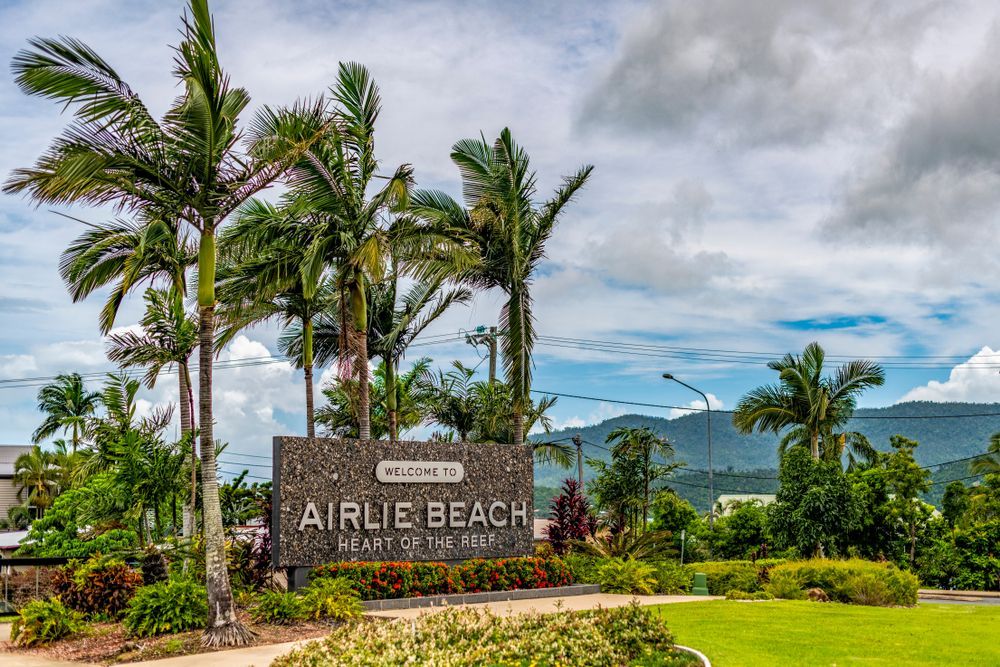 Airlie Beach sign with palm trees and cloudy sky — Apex Antenna Solutions Pty Ltd in Airlie Beach, QLD