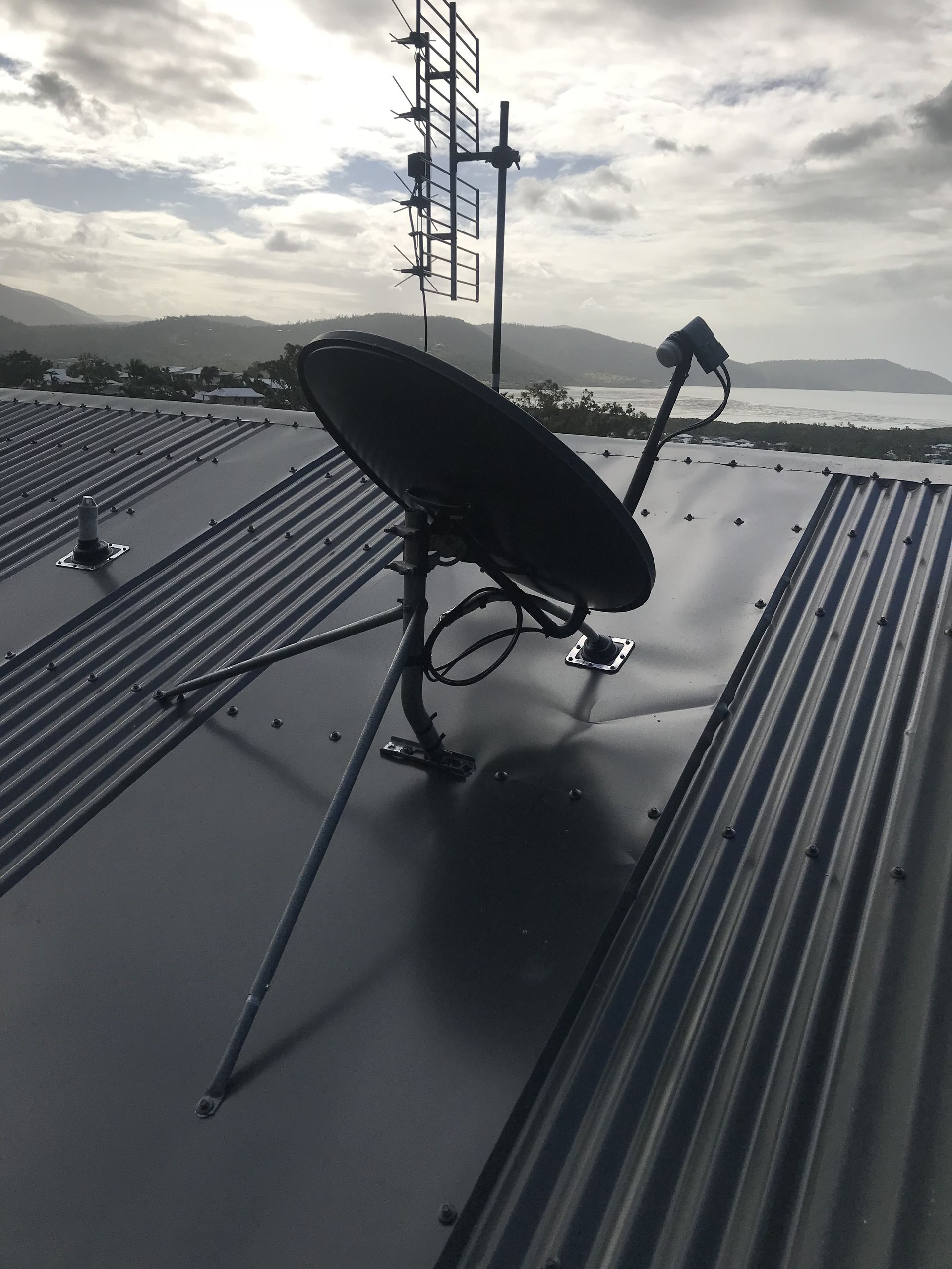 A Grey Satellite Dish Mounted on a House Roof — Apex Antenna Solutions Pty Ltd in Cannonvale, QLD