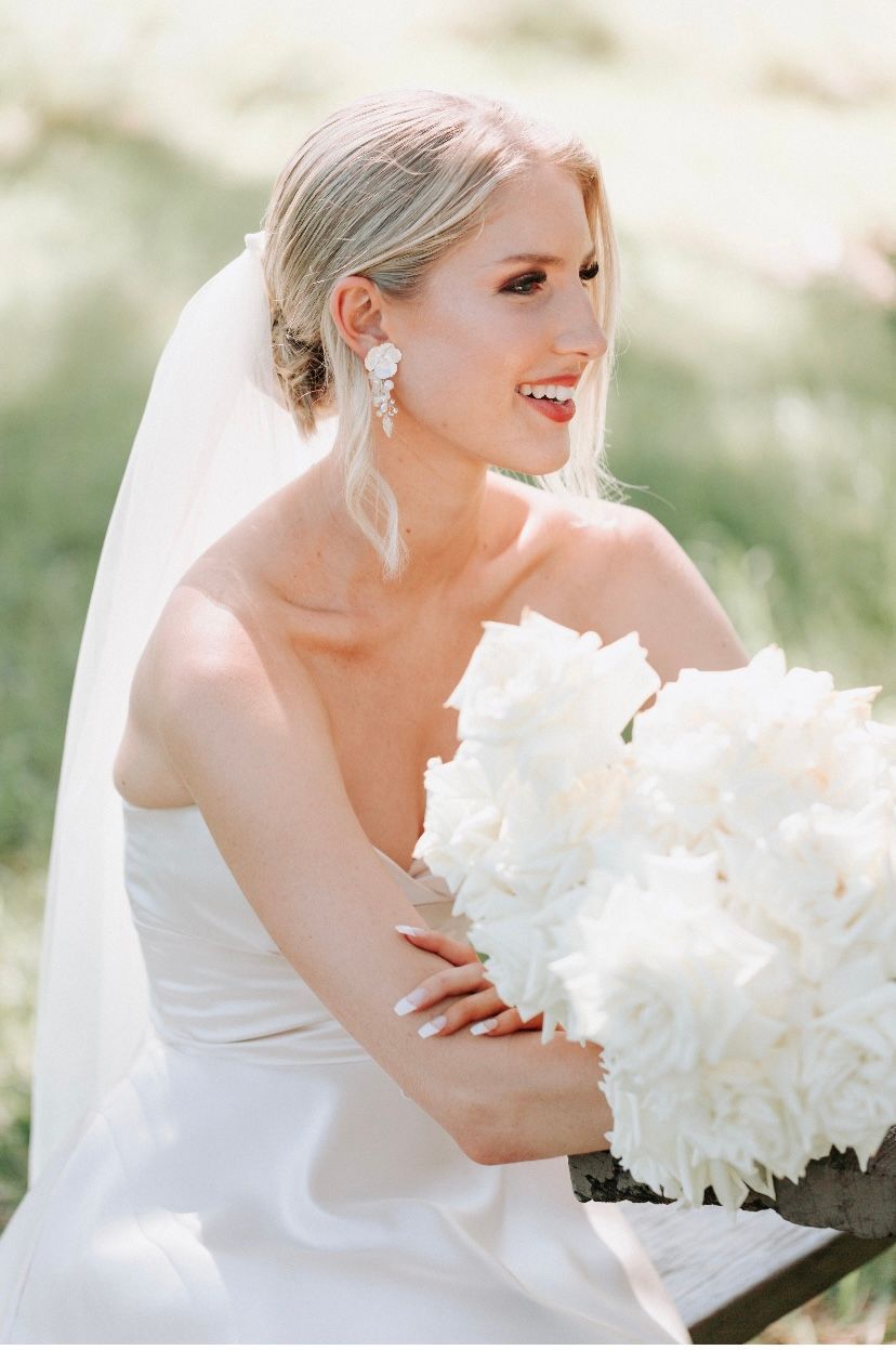 The bride is wearing a veil and holding a bouquet of white flowers.