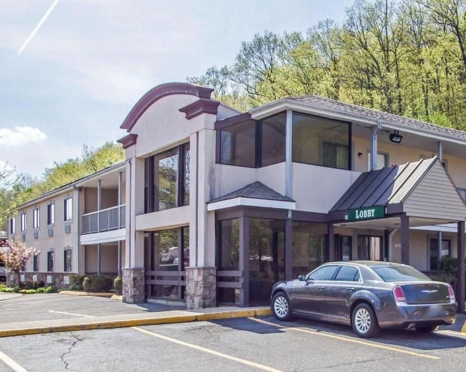 A gray car is parked in front of a hotel