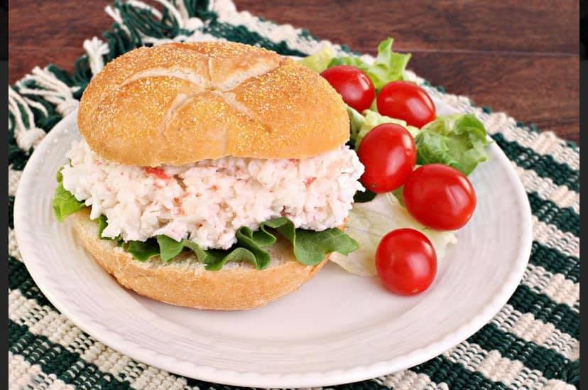 A crab salad sandwich with lettuce and tomatoes on a plate.