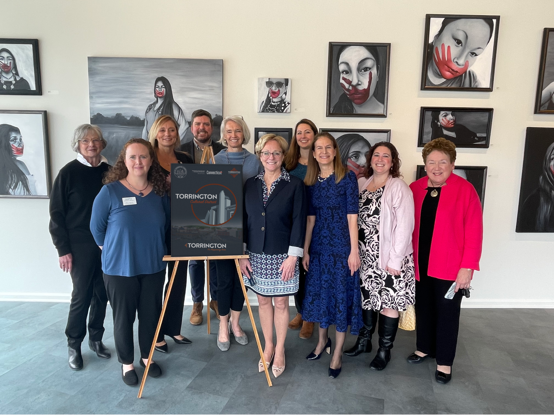 A group of people posing for a picture in front of paintings