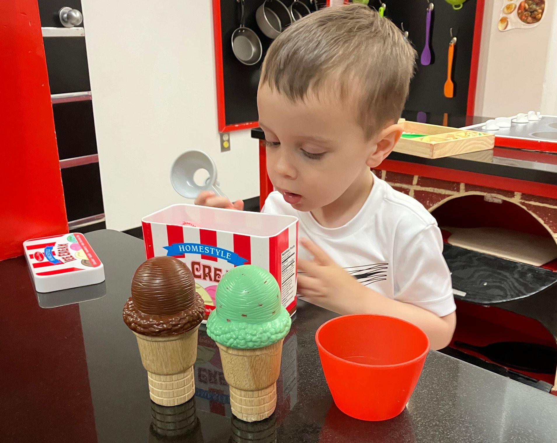 A young boy is playing with ice cream cones on a table.