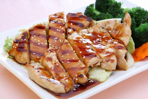 A white plate topped with grilled chicken and broccoli.