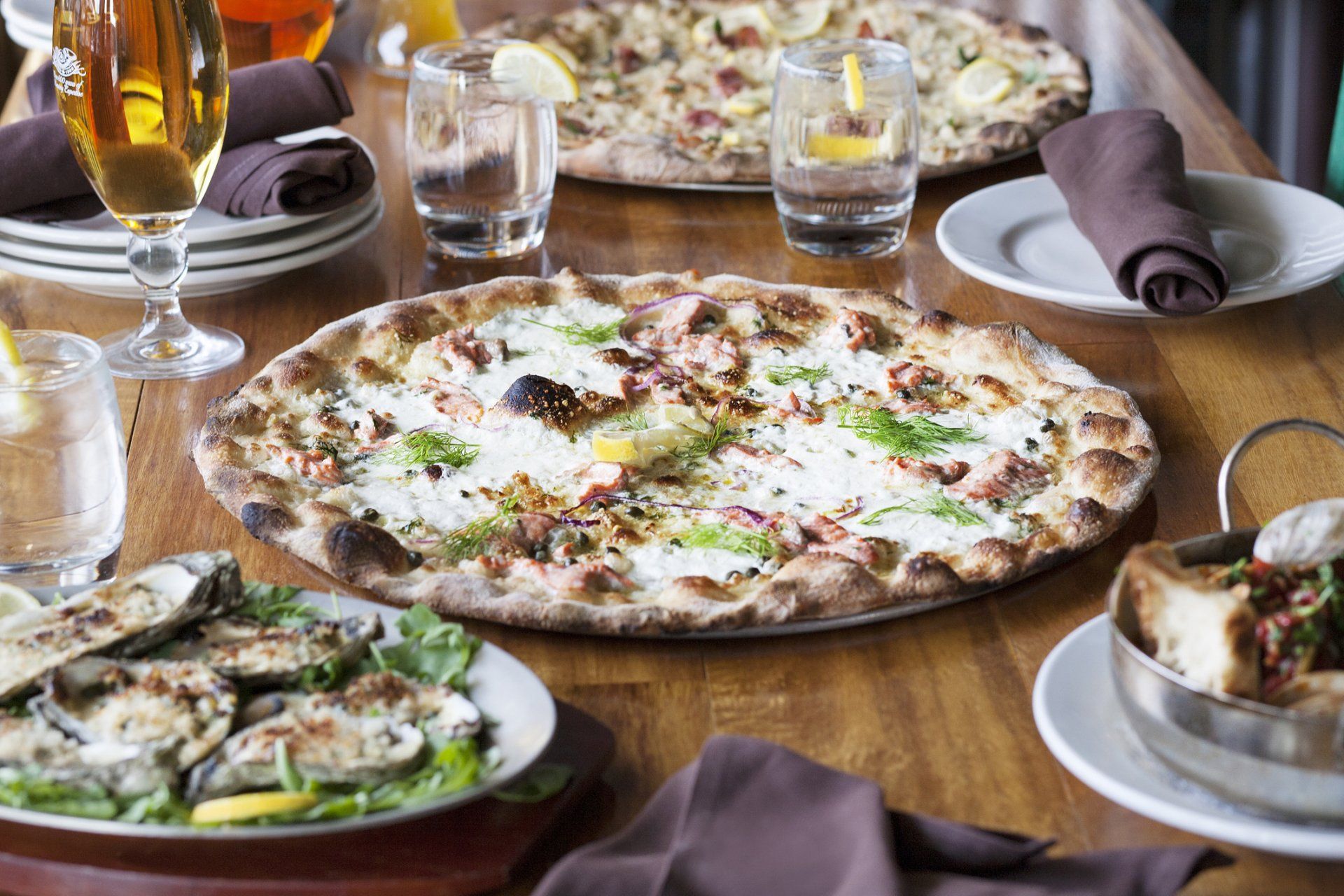 A wooden table topped with plates of food and a pizza.