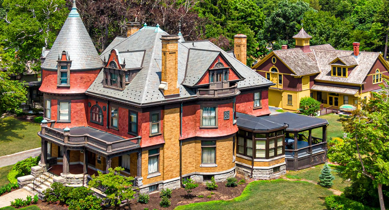An aerial view of a large brick house surrounded by trees.
