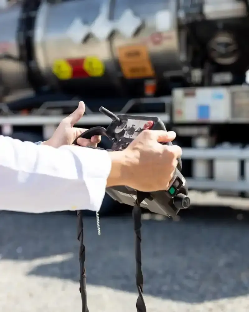 Un camion MAN bianco all'interno di un garage, con un container grigio scuro, parcheggiato davanti a una grande porta rossa.