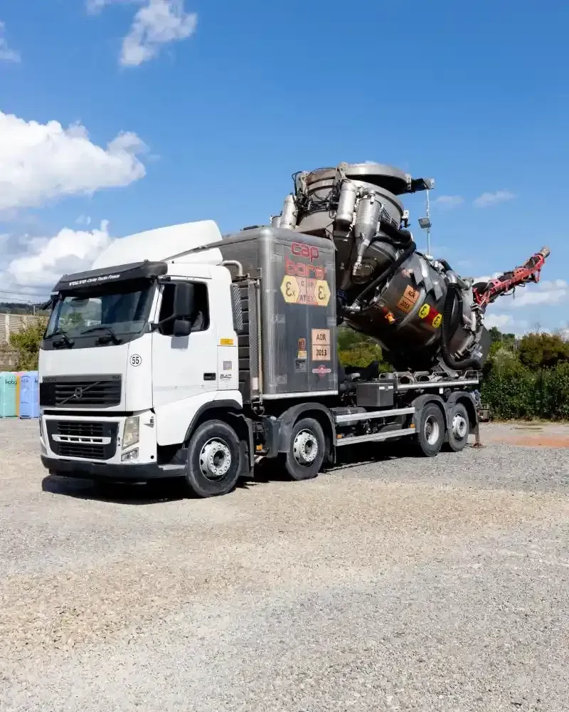 Un camion della nettezza urbana blu e bianco parcheggiato accanto a un edificio beige chiaro.