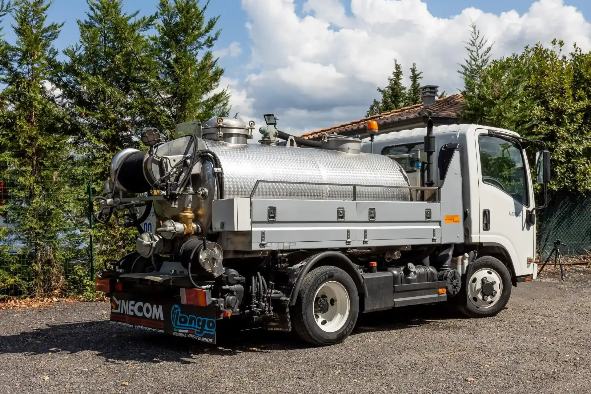 Camion settico blu e bianco, parcheggiato all'aperto, con tubi flessibili e comandi.