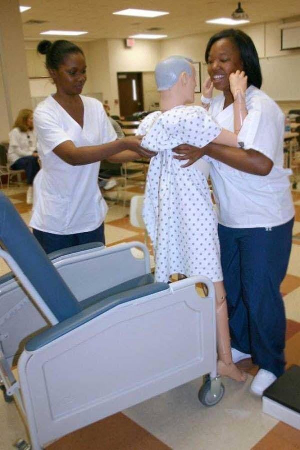 Two Nurses Are Helping a Mannequin Into a Hospital Chair