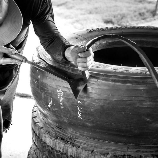 A black and white photo of a man working on a tire