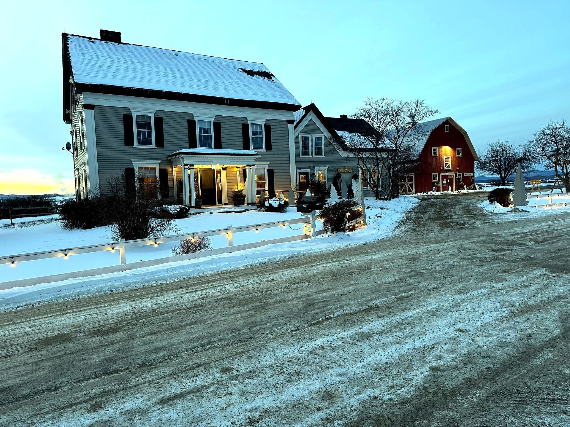 The Wildflower Inn and red barn under snow at dusk, Lyndonville, Vermont