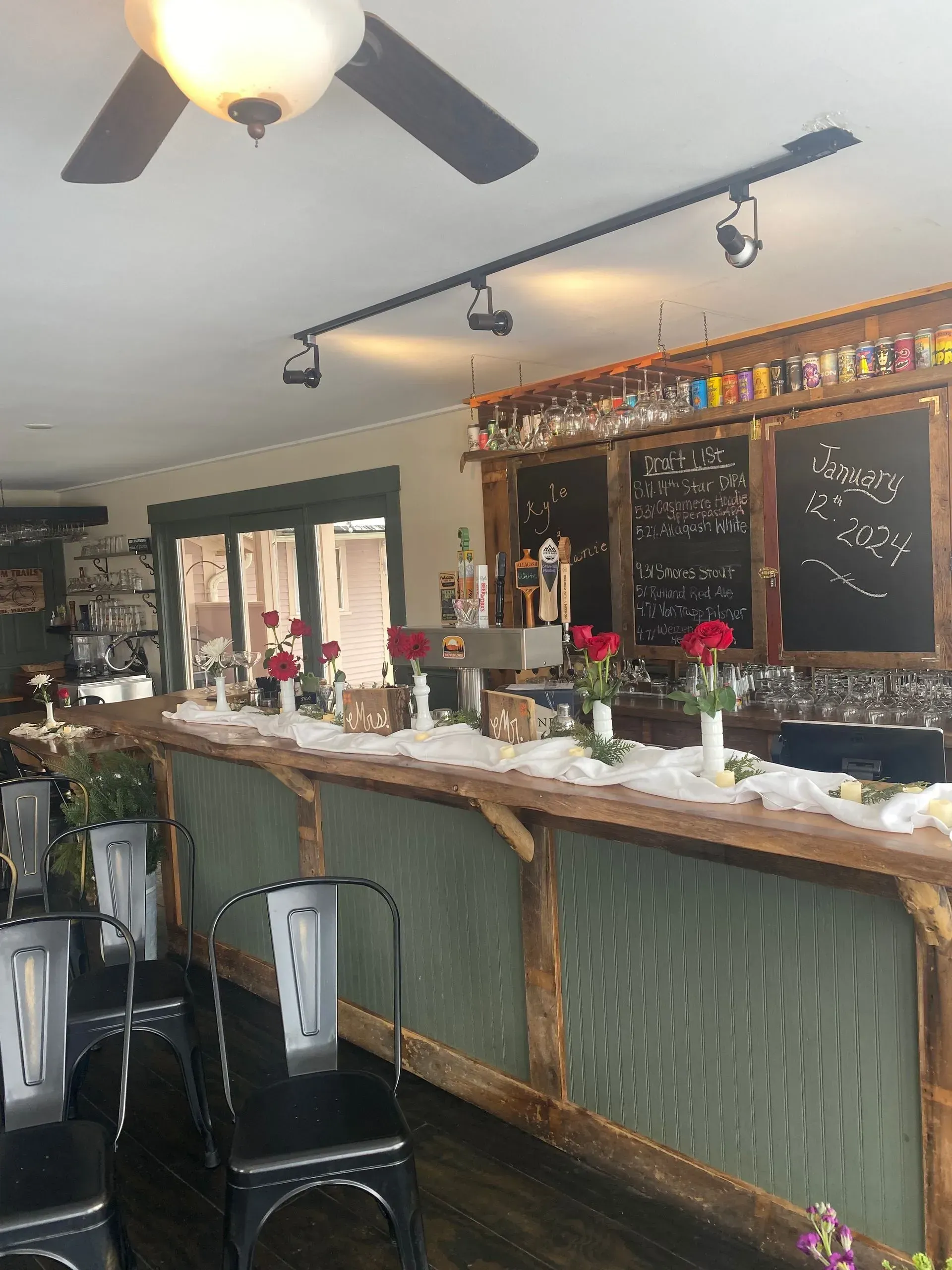 Cozy bar interior with wooden counter, stools, hanging lights, and holiday decorations