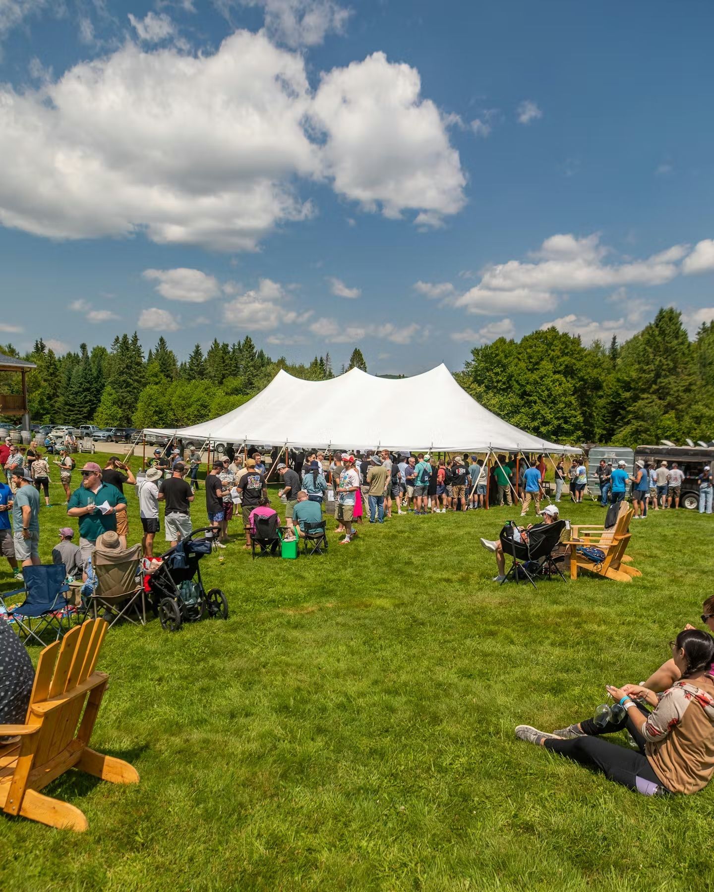 Crowd seated on grass at Hill Farmstead Brewing's festival near a large white tent under a blue sky