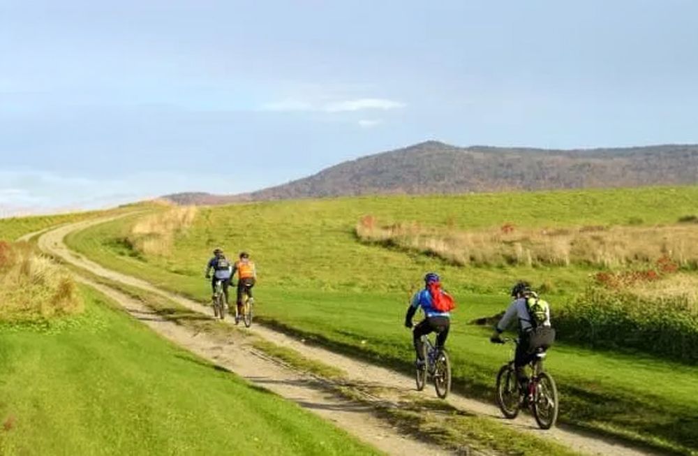 Mountain bikers riding Kingdom Trails on The Wildflower Inn property with Burke Mountain views in Ea