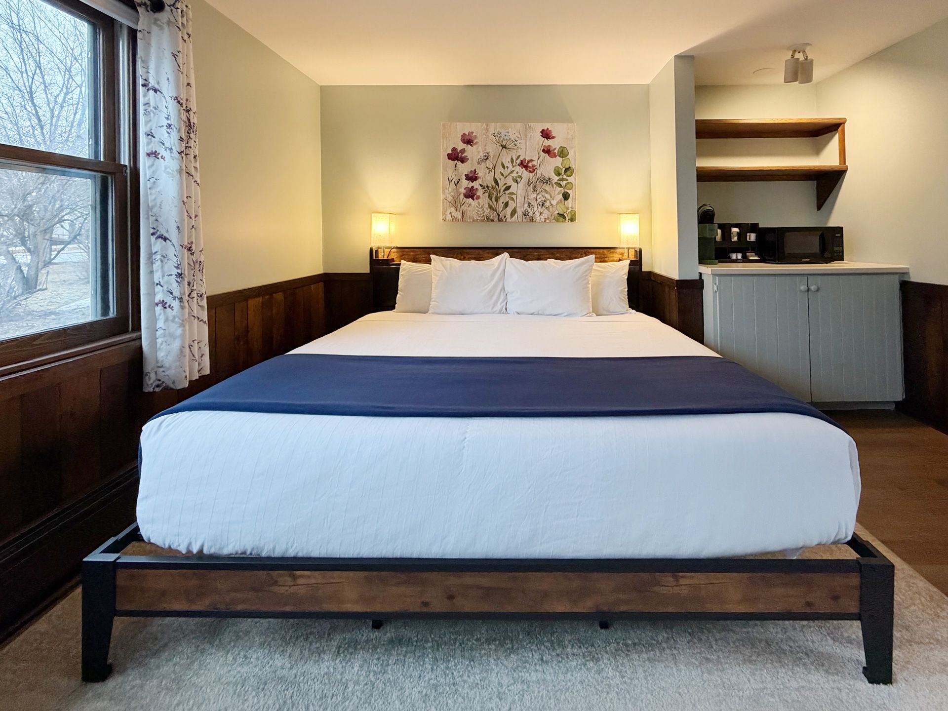 Cozy bedroom with a queen bed, bedside lamps, window, and built-in shelves