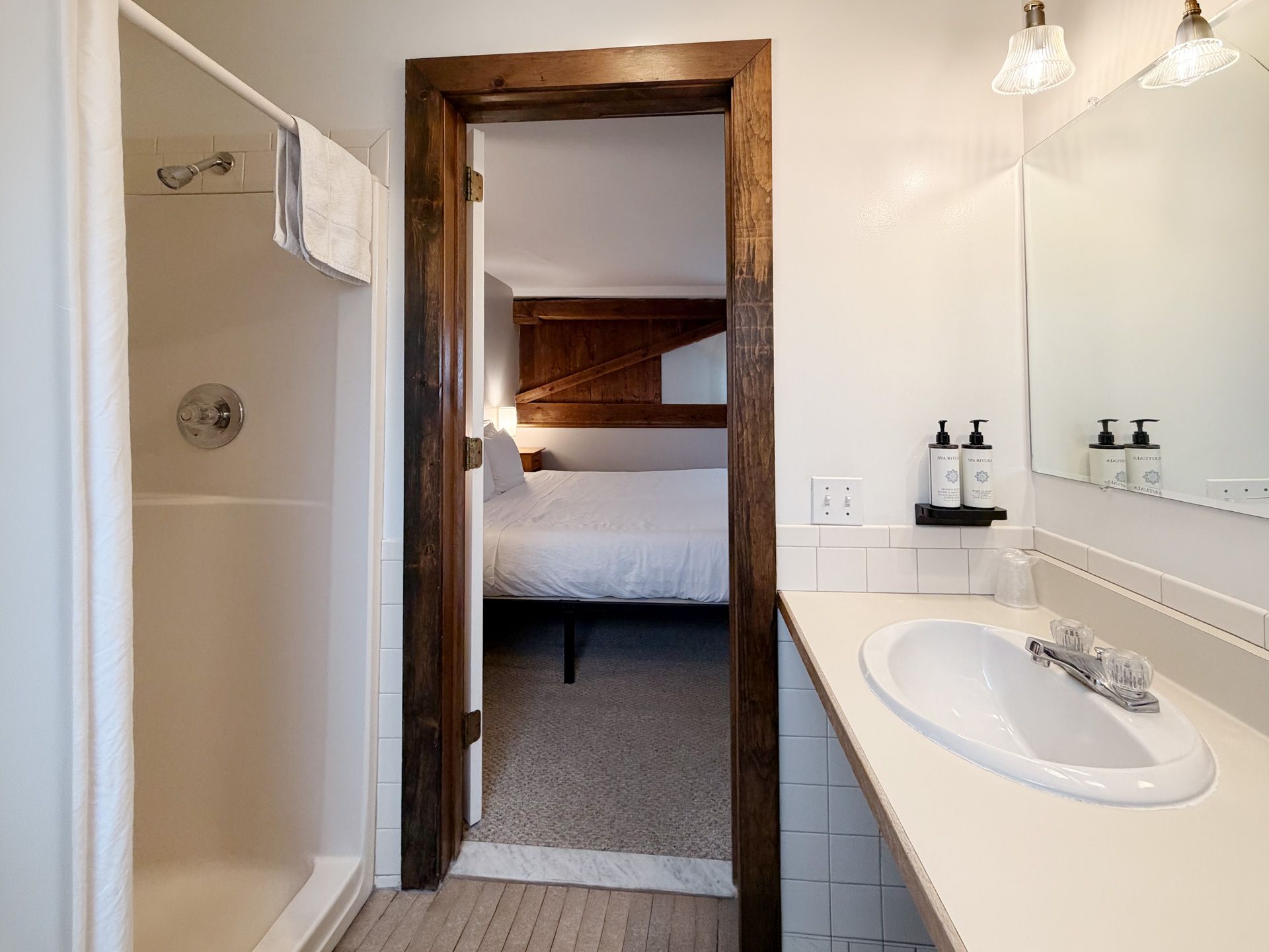 Bathroom vanity and shower leading to a bedroom through an open doorway