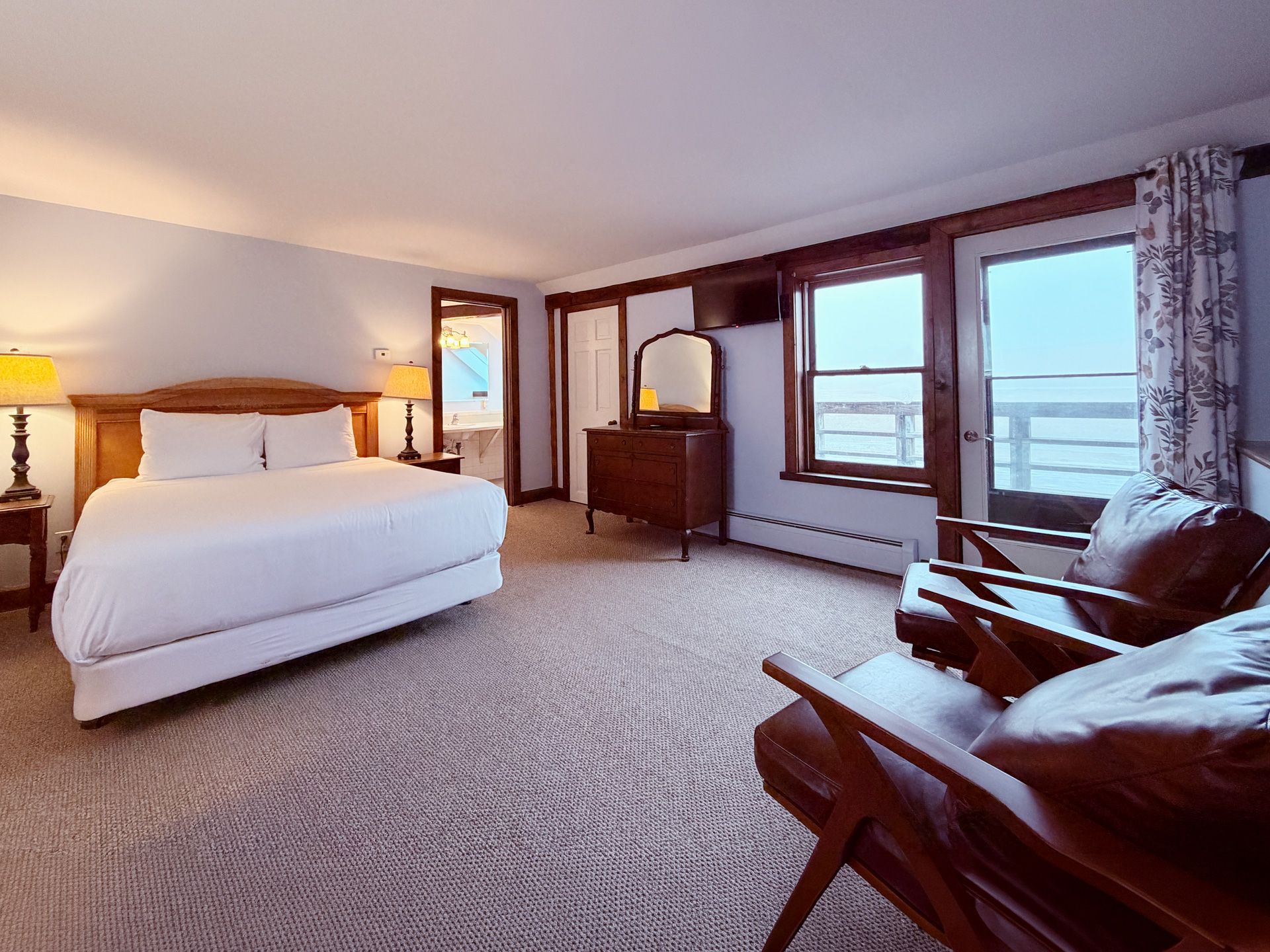 Hotel room with two beds, a sitting chair, and large windows overlooking the water