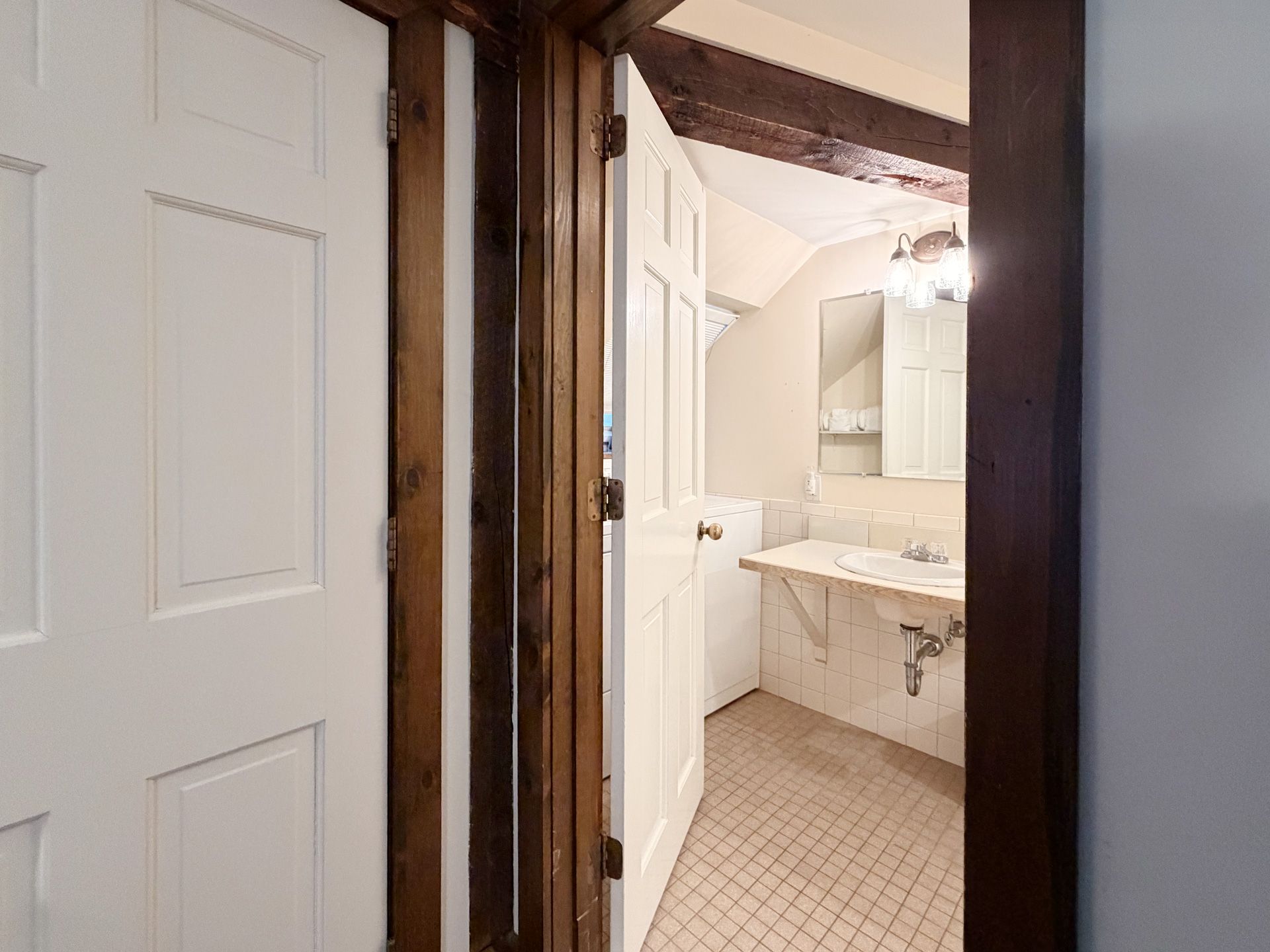 Bathroom doorway with white cabinets, tiled floor, and a marble vanity sink visible inside