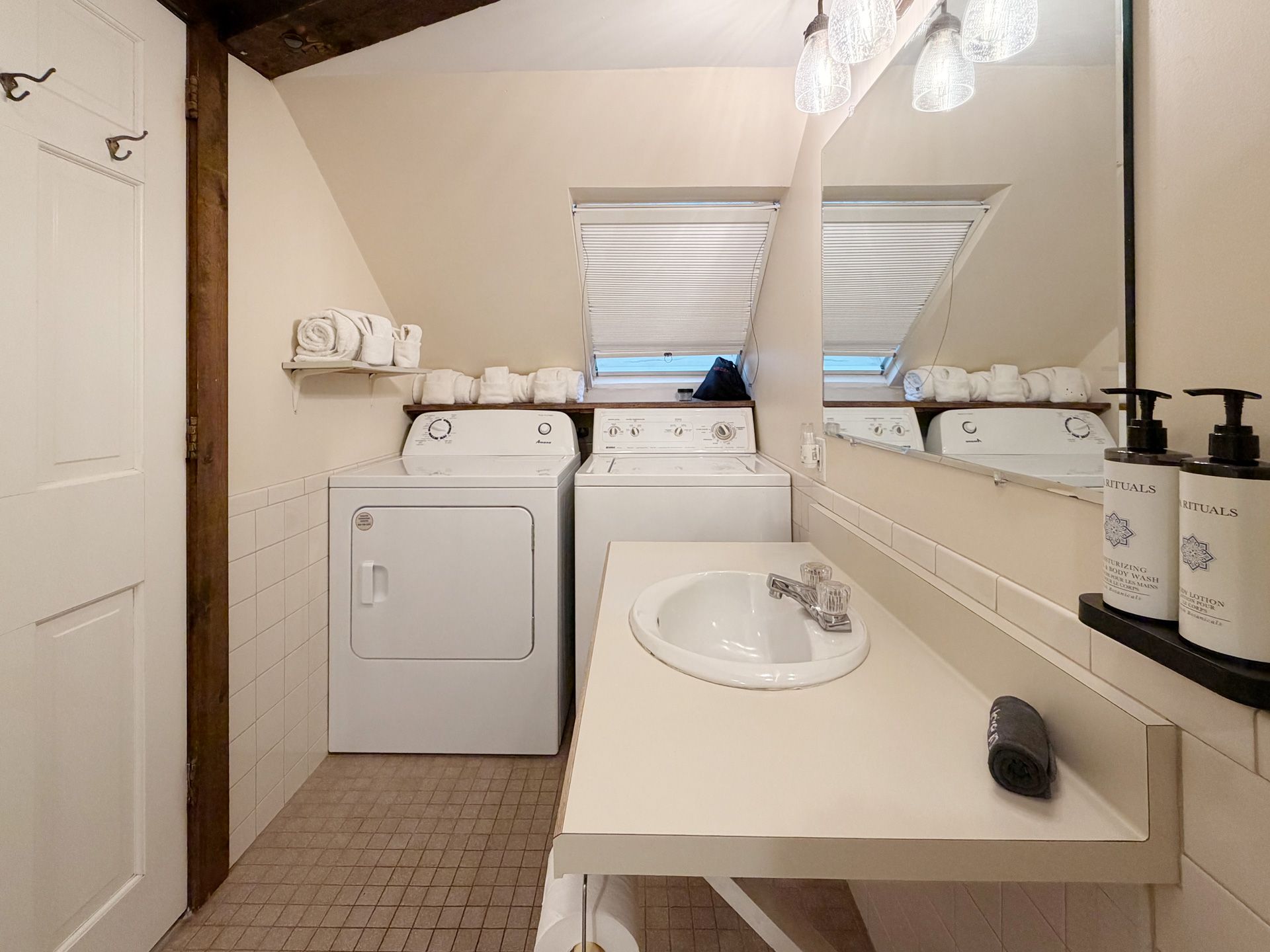 Small bathroom with sloped ceiling, sink vanity, washer and dryer, and skylights.