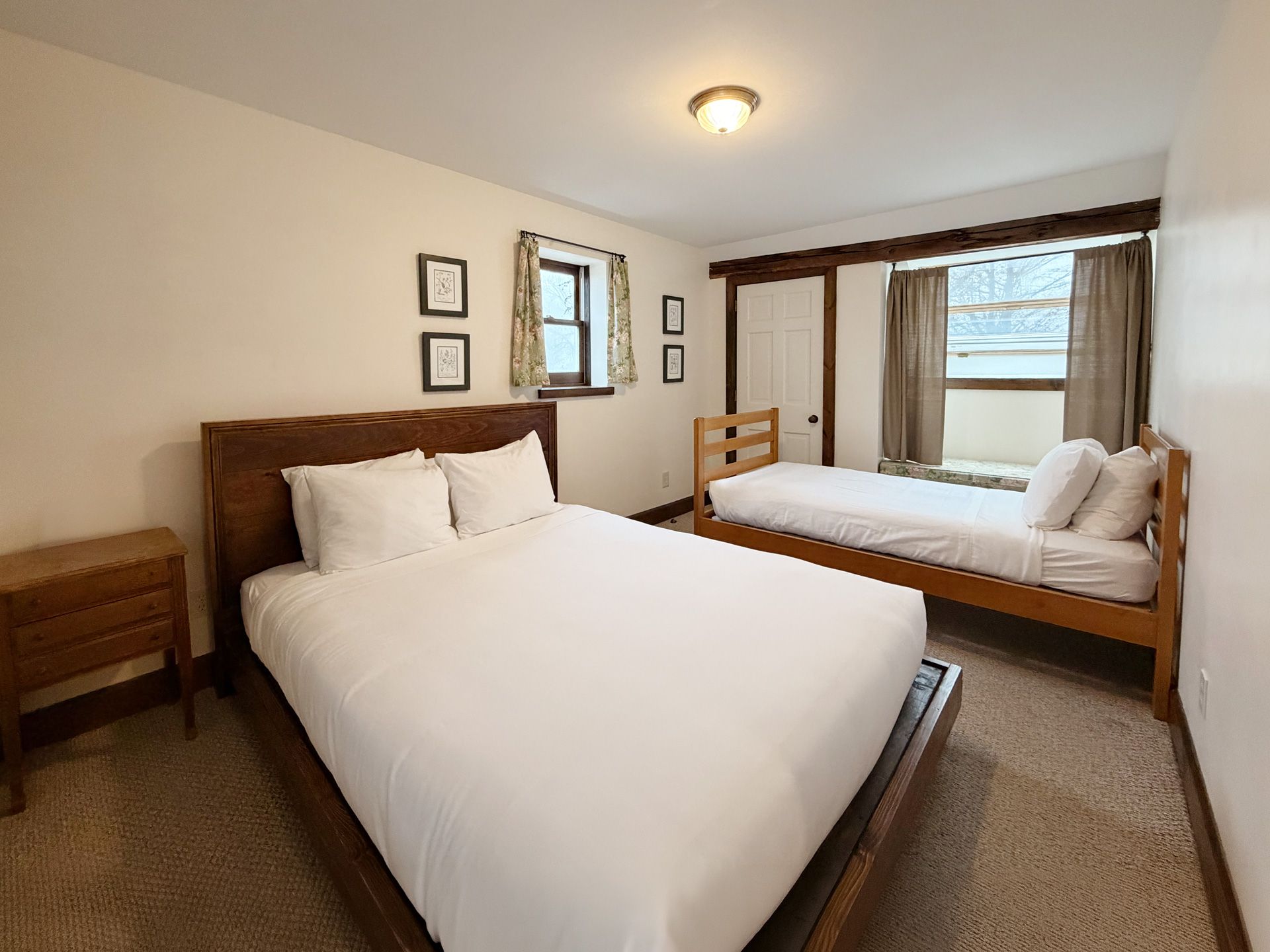 Bedroom with a bed, daybed, mirror, and window in a bright neutral-toned room