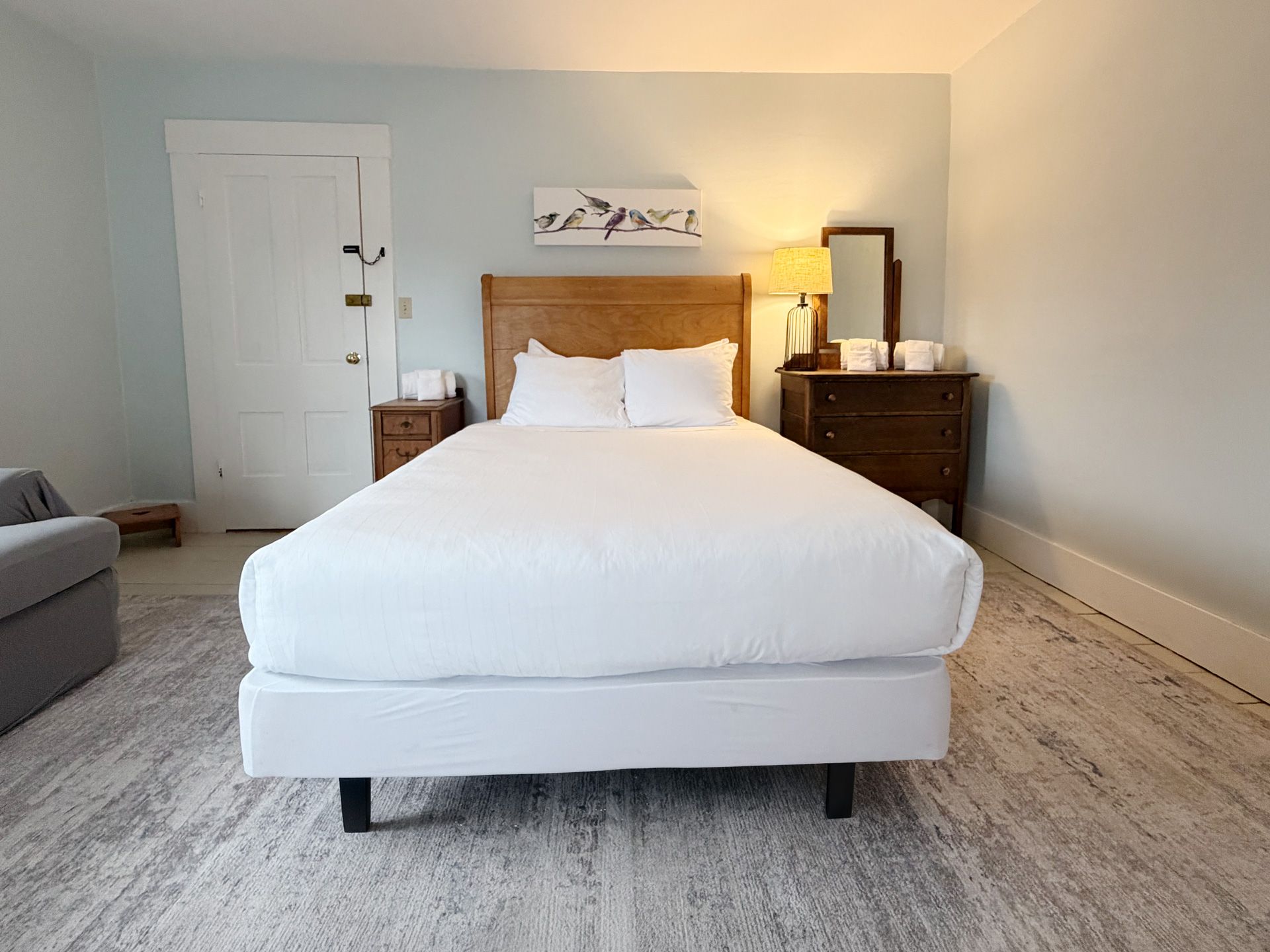 Minimal bedroom with a white bed, wooden nightstands, and light gray walls