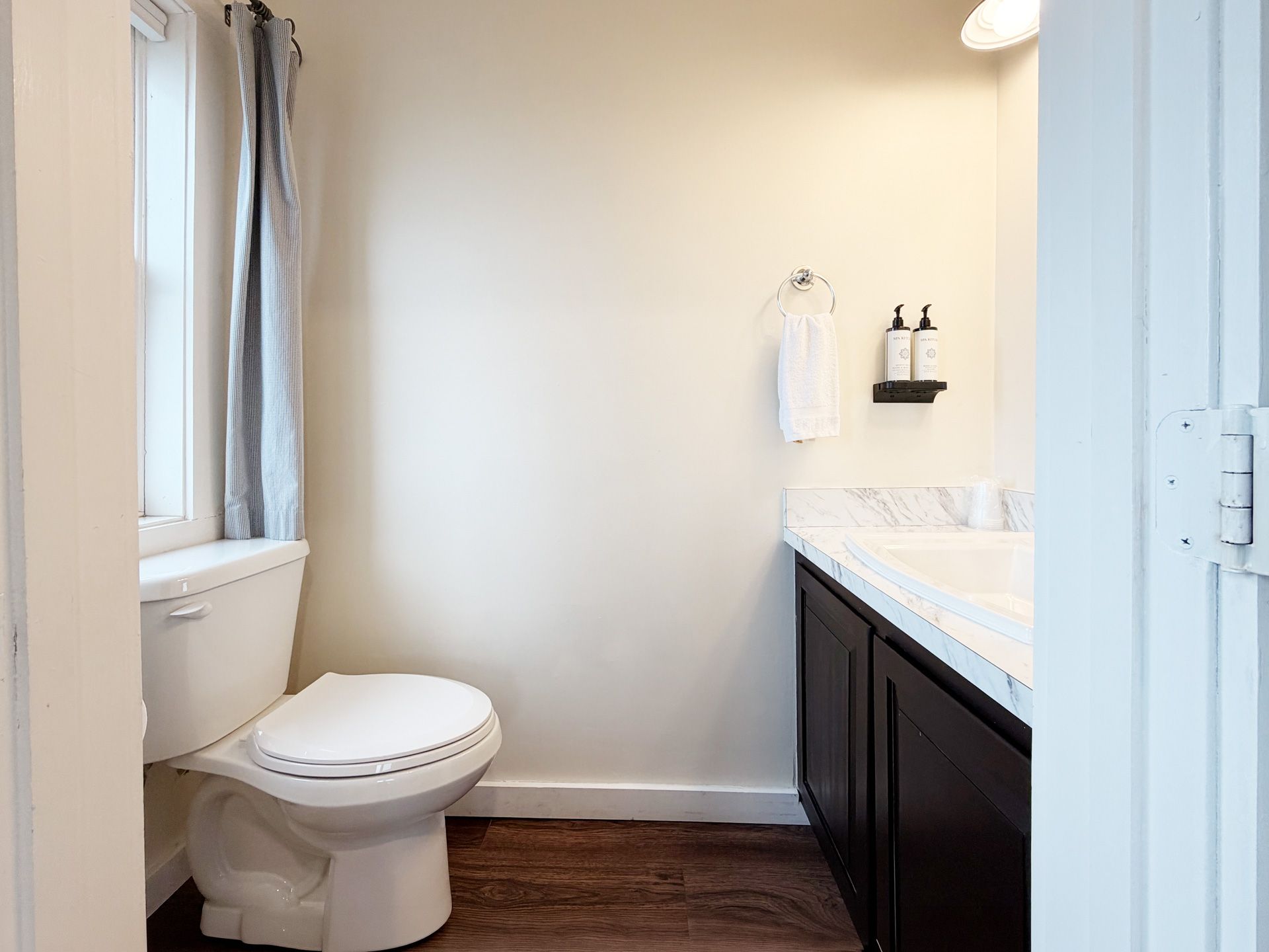 Small bathroom with a toilet, vanity, mirror, and white walls.