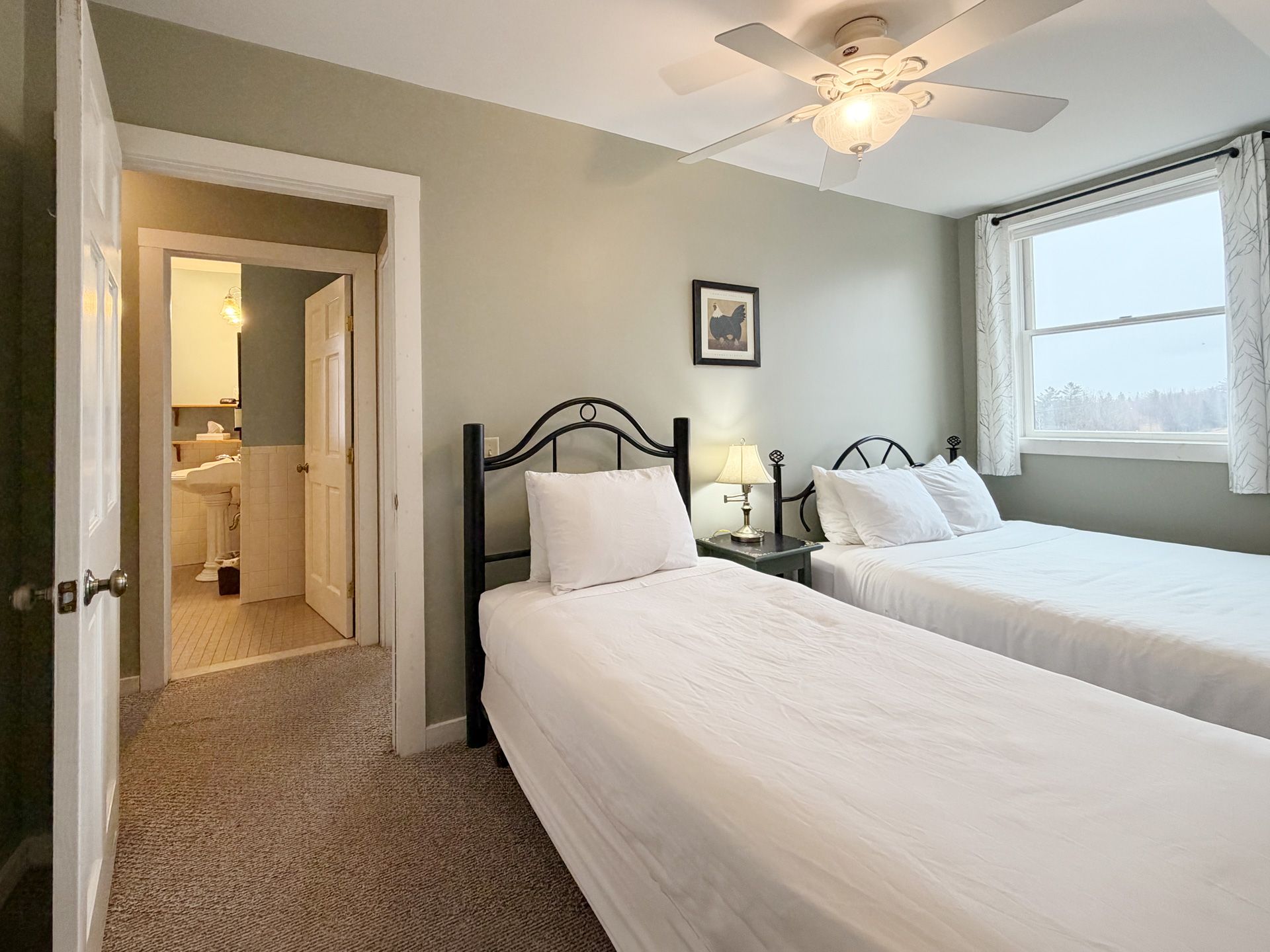 Small bedroom with two twin beds, white bedding, carpet, and a window with daylight.