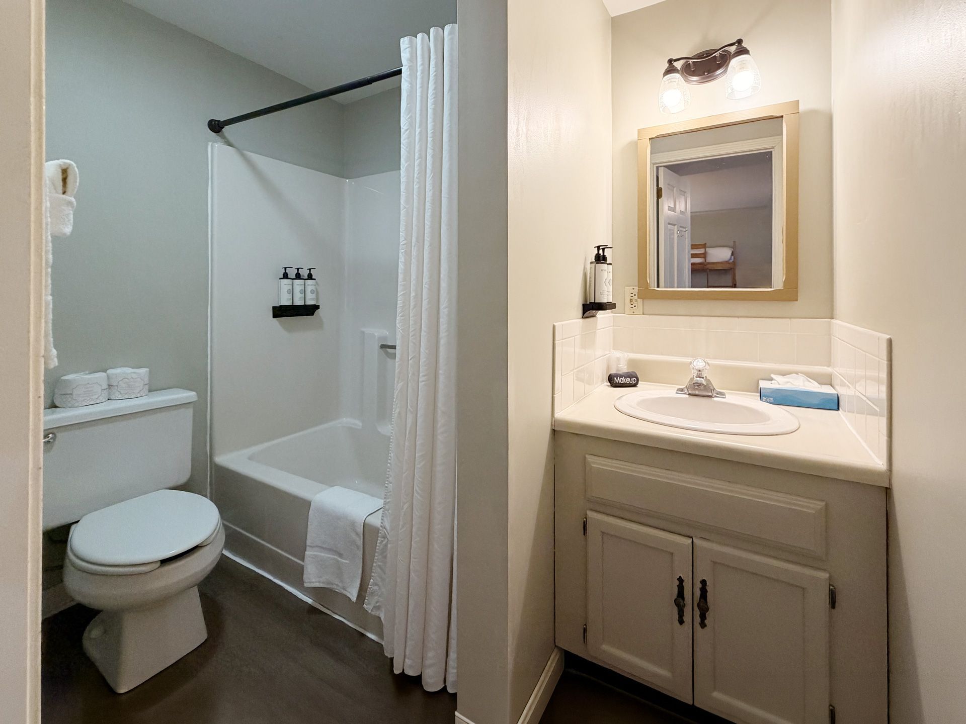 Small bathroom with toilet, shower curtain, and vanity with mirror and sink.