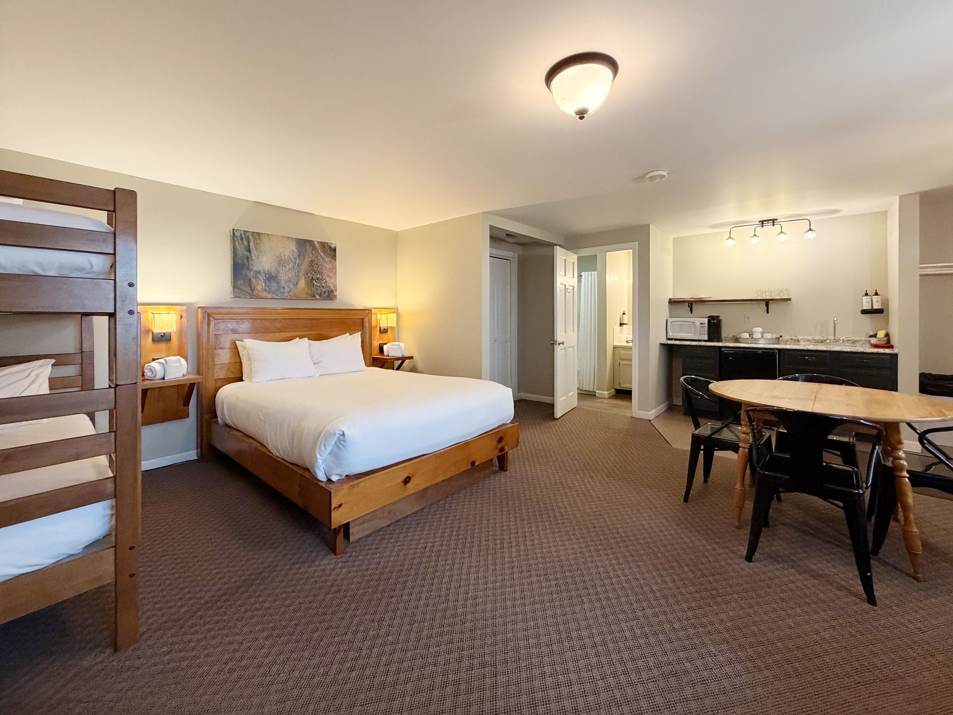 Spacious hotel room with bed, kitchenette, dining table, and carpeted floor