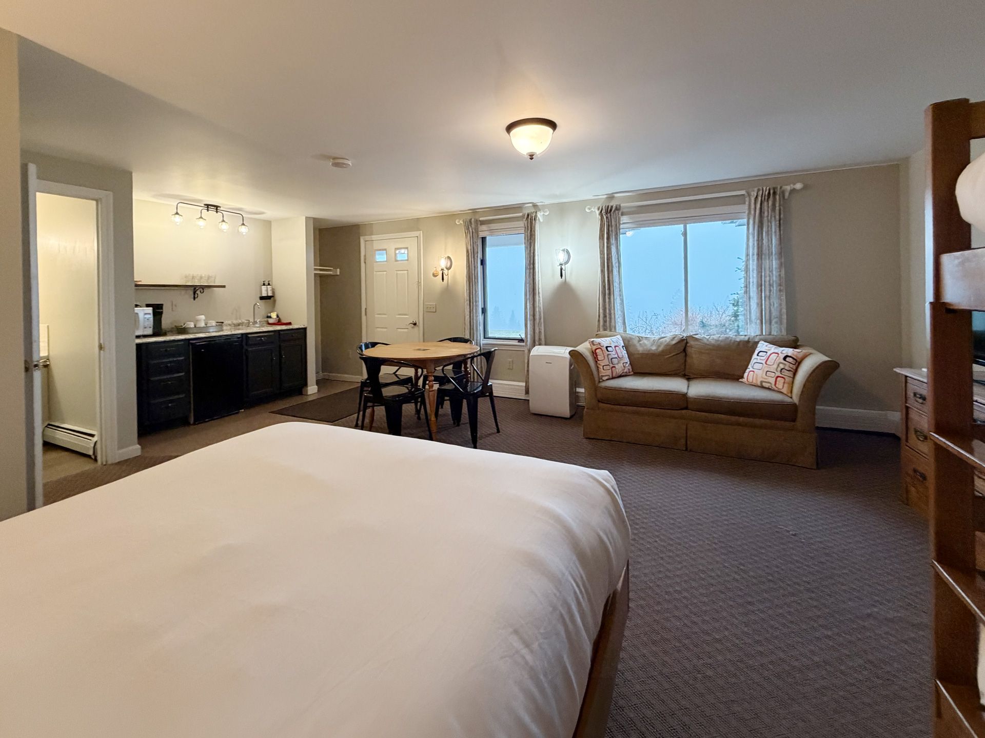 Hotel room with two beds, sofa, desk, and large windows overlooking water