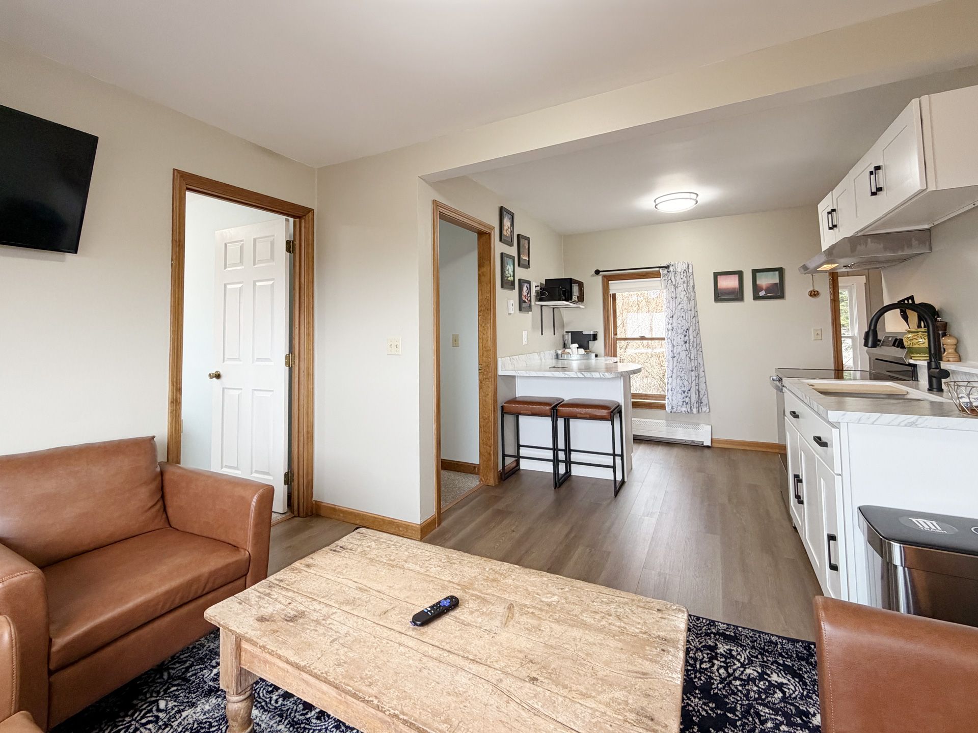 Cozy open-plan living room and kitchen with brown sofa, wood table, and white cabinets
