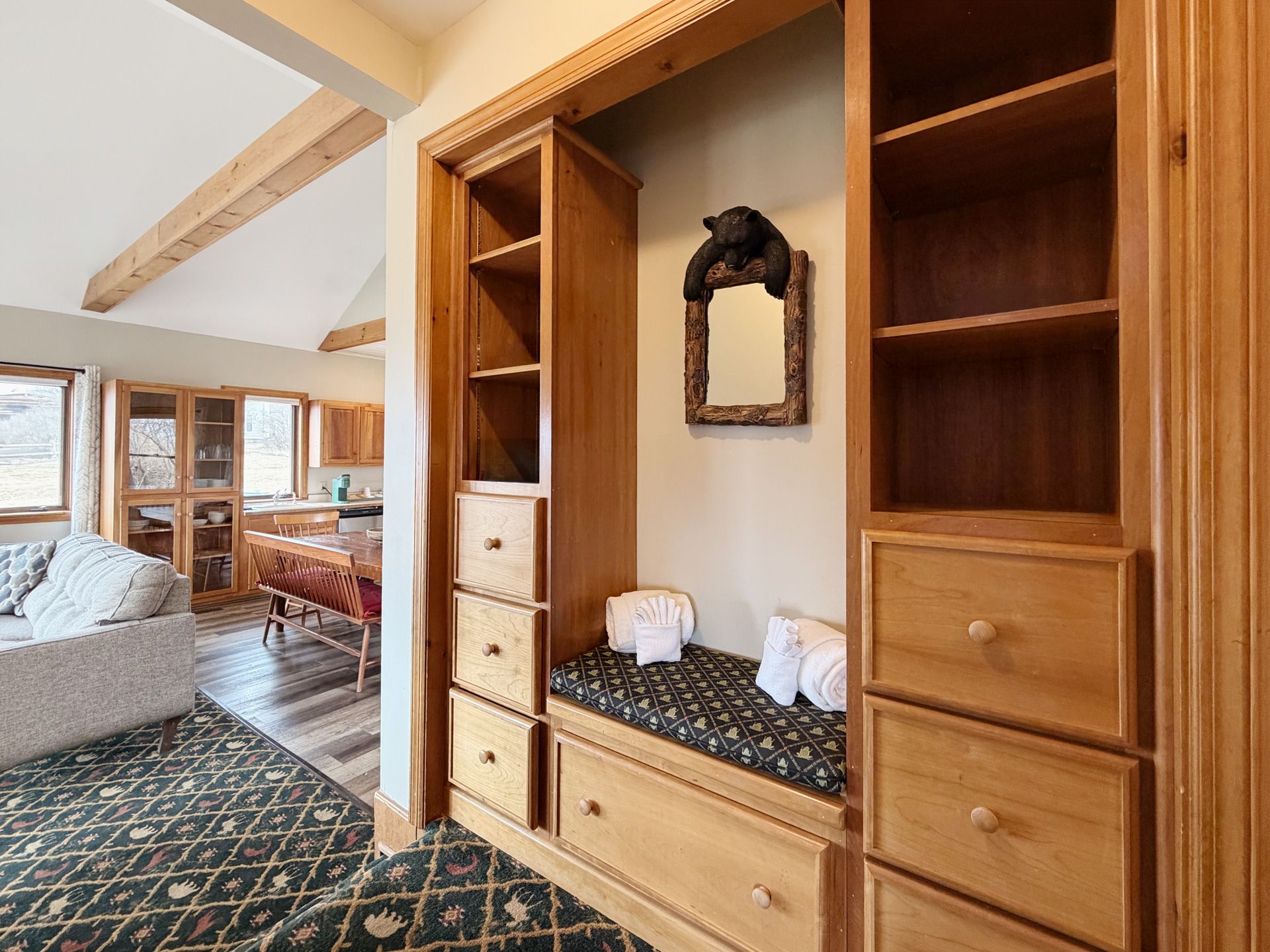 Wooden bedroom closet with drawers, shelves, mirror, and built-in bench in a bright rustic interior