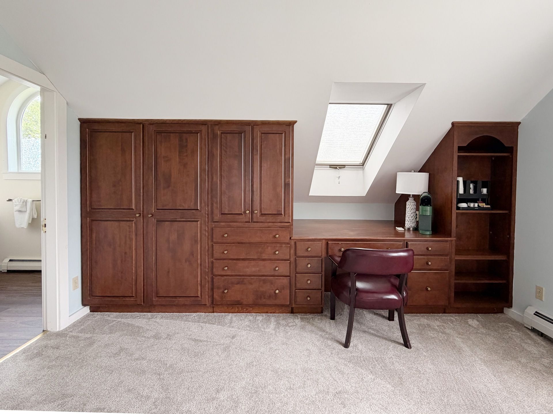 Bedroom with wood wardrobe, dresser, chair, and skylight under sloped ceiling