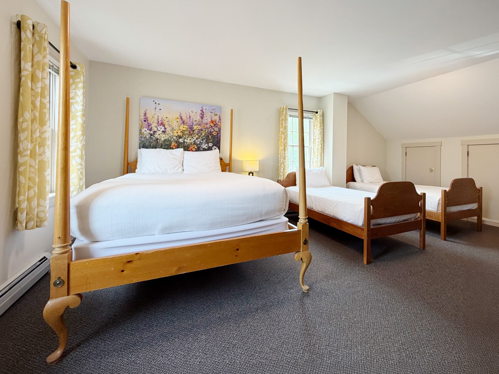 Bright bedroom with two wooden four-poster beds, white bedding, and yellow curtains