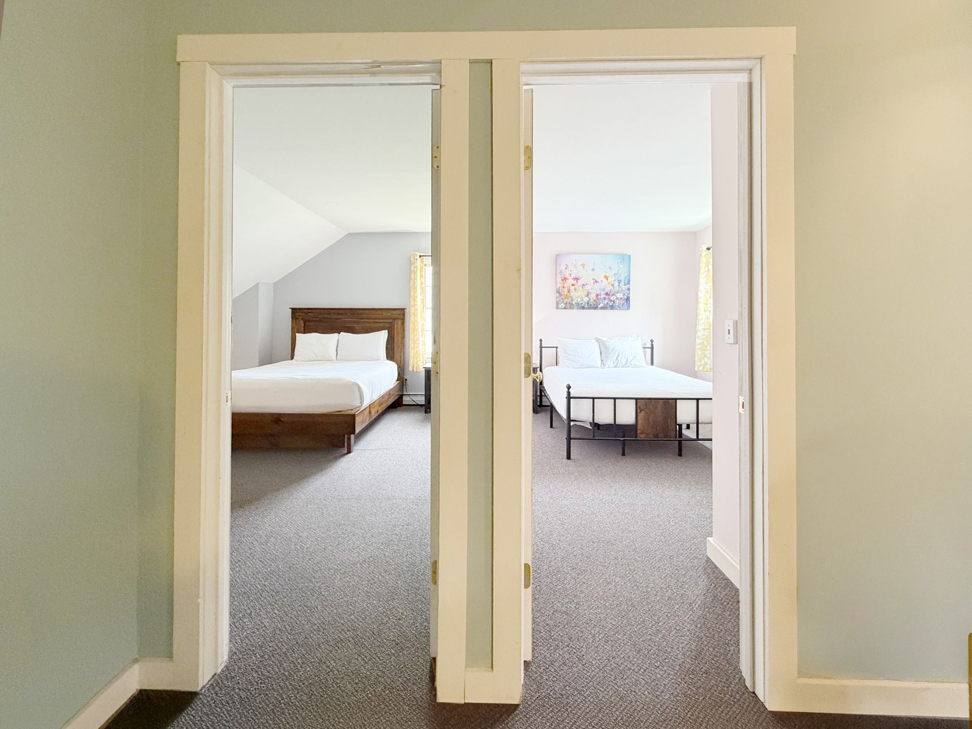 Interior hallway with two open doorways, showing a bedroom on the left and a dining area on the right.