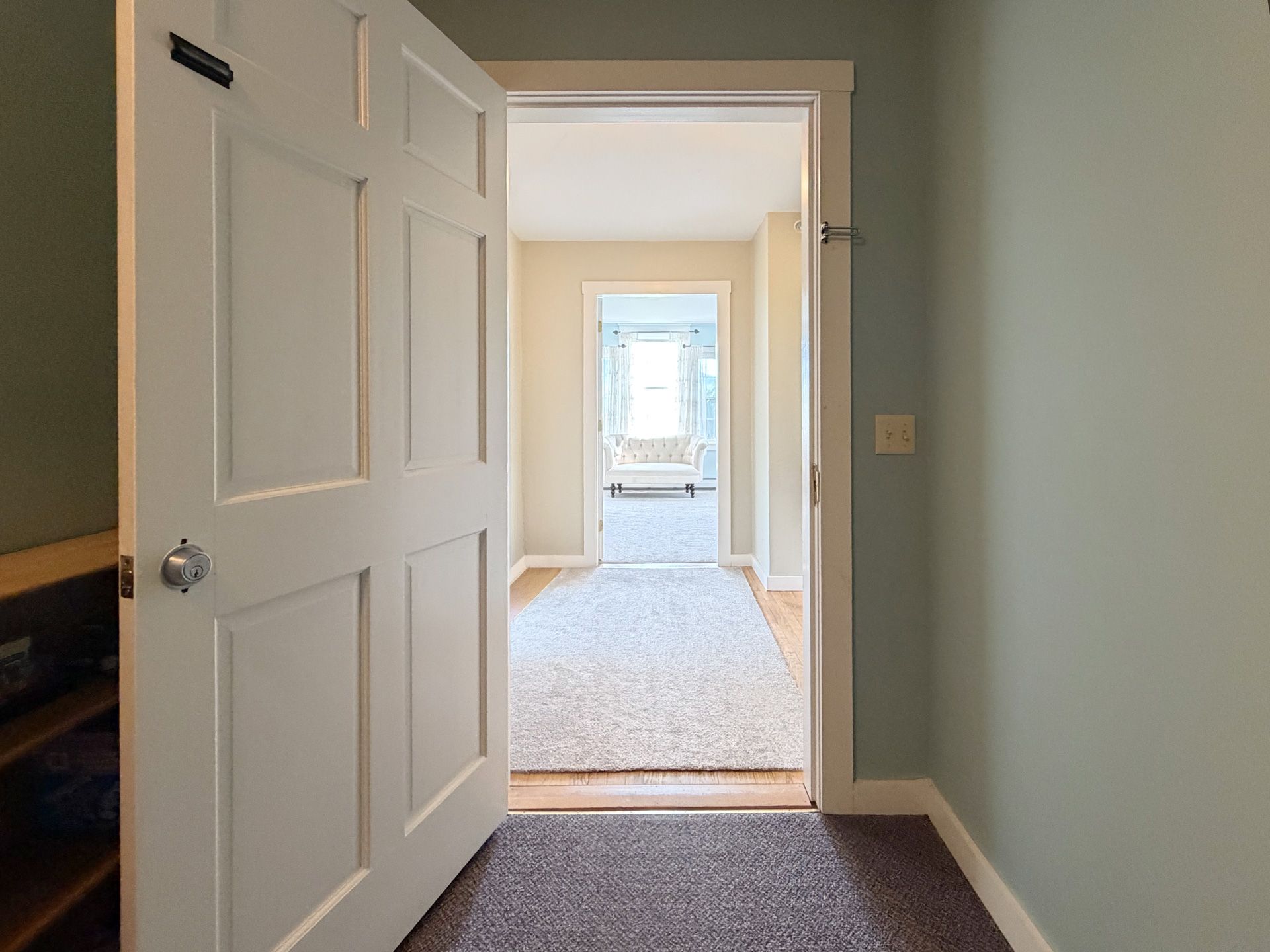 Open white doorways framing a bright carpeted hallway and room beyond