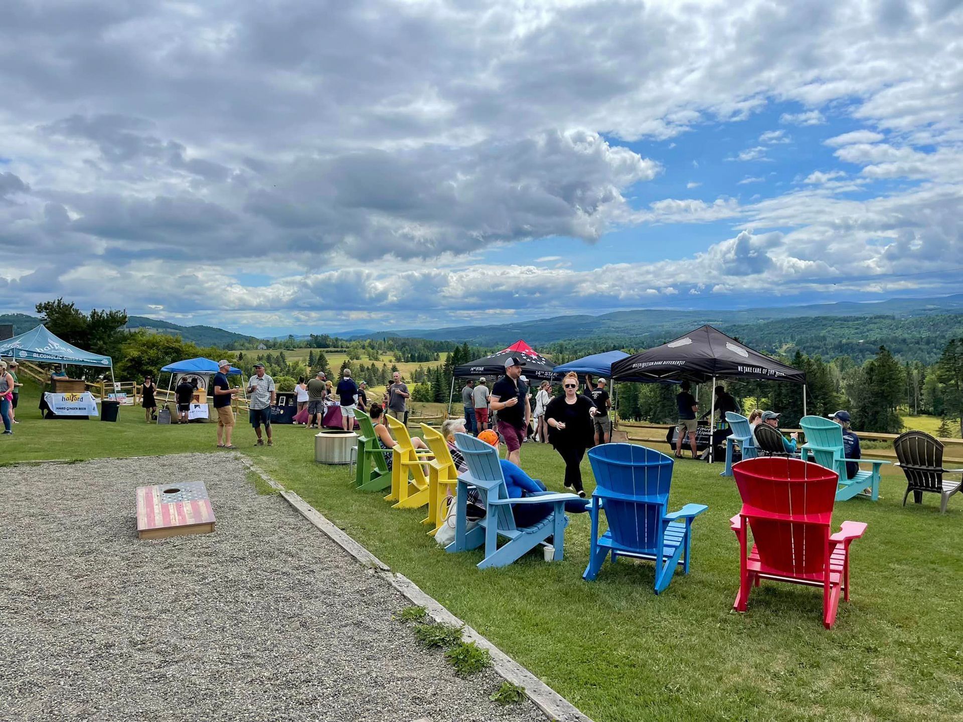 Outdoor scenic overlook with people socializing on colorful chairs under a cloudy sky.