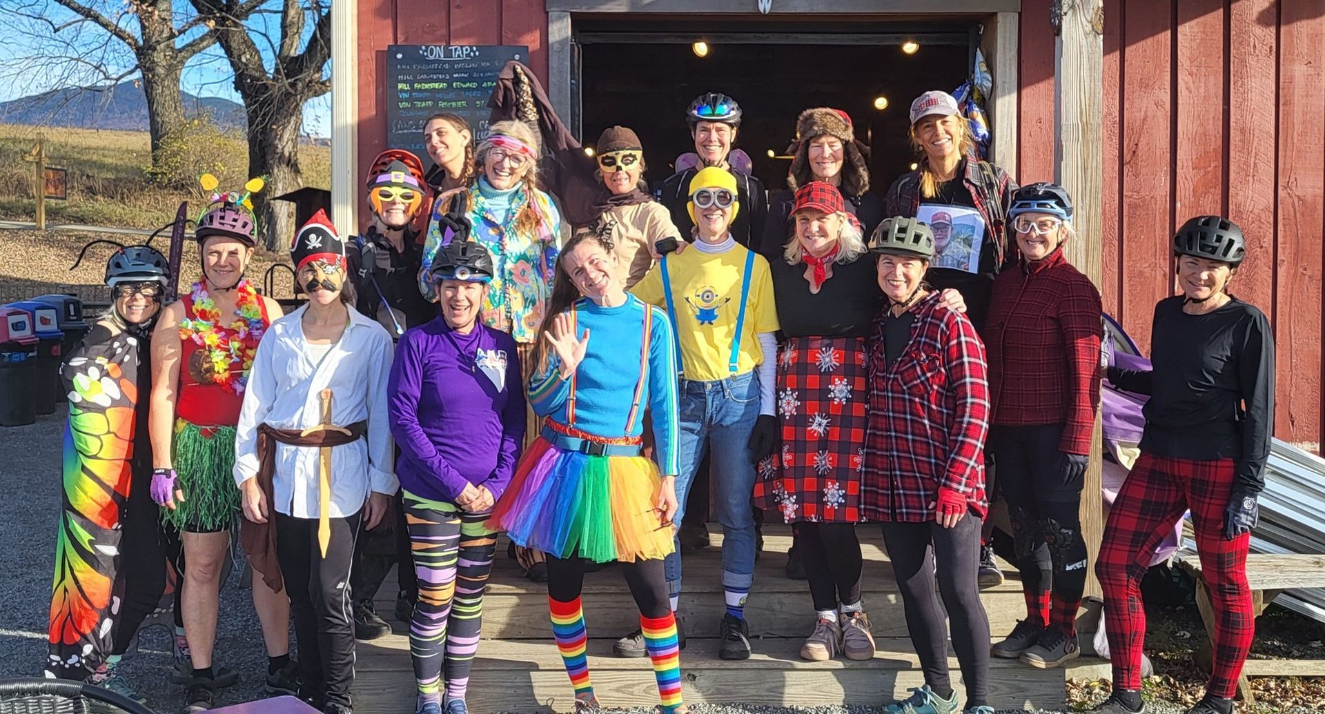 Group of people in colorful costumes posing outside a building, smiling and standing together