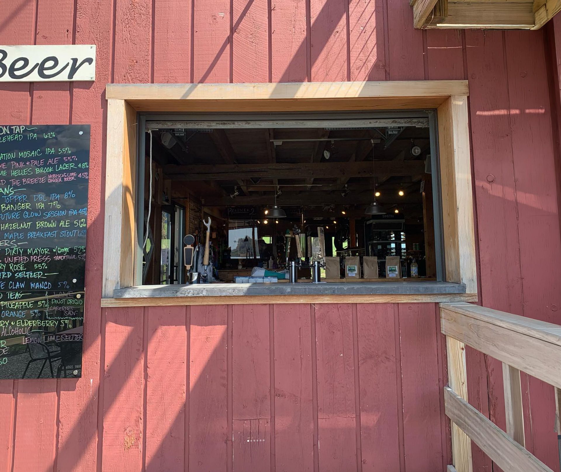 Red wooden building with a large serving window into a dim bar interior.