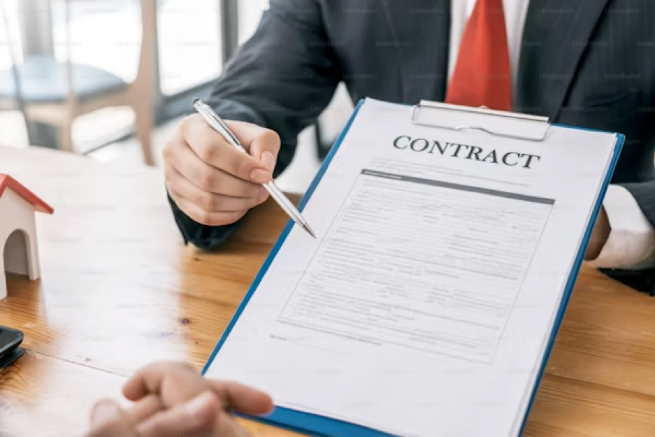A person in a suit holds a pen and points to a document labeled 