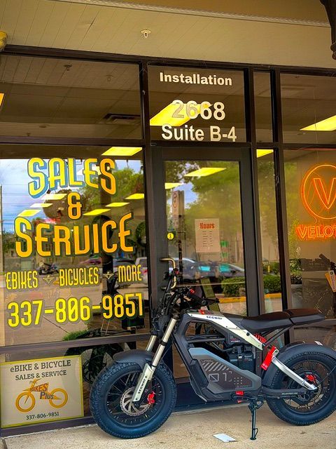 Storefront window with “Sales & Service” signage and a black electric bike parked outside.