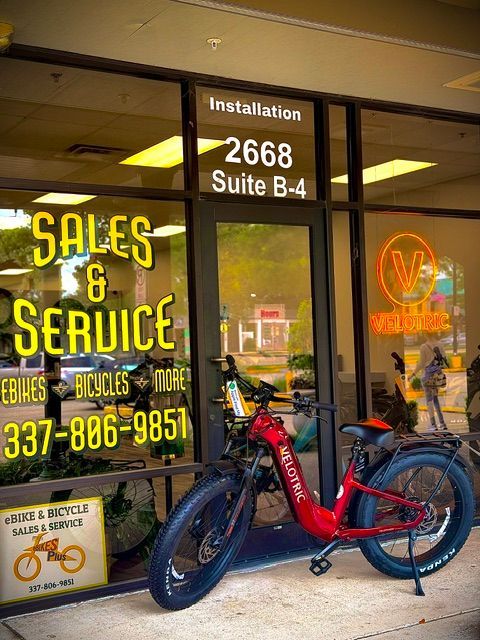 Red electric bicycle parked outside Sales & Service bike shop storefront
