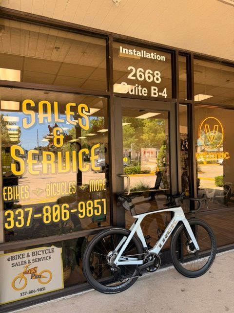 Bike shop storefront with SALE & SERVICE signage and a white bicycle parked outside