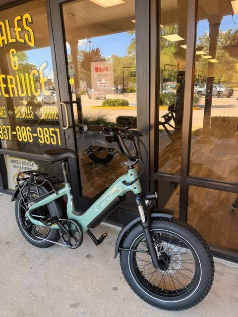 Mint-green electric bike parked outside a shop entrance with glass doors.