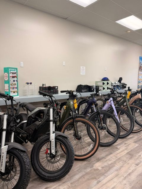 Row of bicycles and electric bikes lined up indoors in a bright room